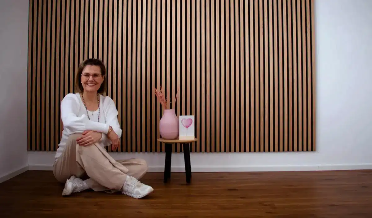 Heidi von Ginger and Grape sitzt entspannt vor einer gem&uuml;tlichen Holzwand und l&auml;chelt in die Kamera.