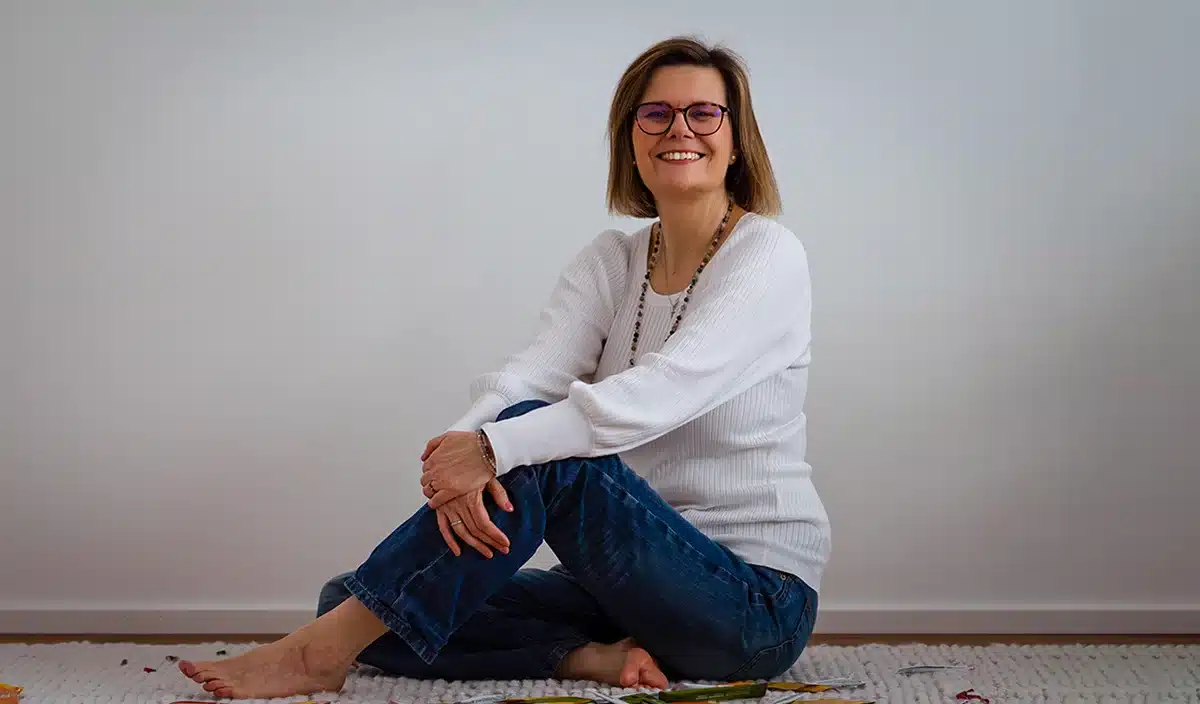 Heidi Pritschet, Familiencoach, sitzt entspannt auf dem Teppich und l&auml;chelt.